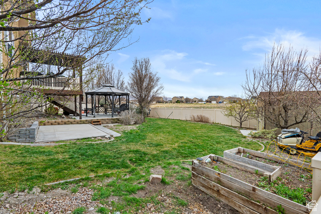 View of yard with a patio, a gazebo, fence, and a vegetable garden