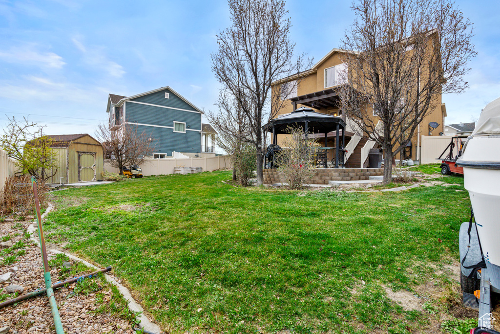 View of yard with an outbuilding, fence, a storage shed, and a gazebo