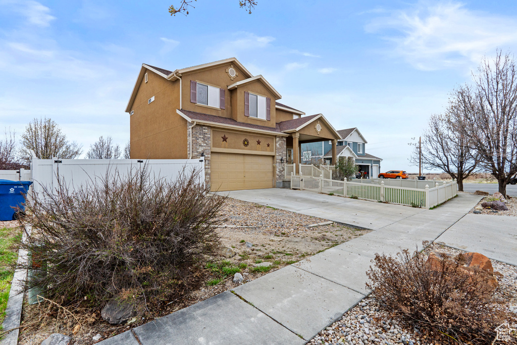Traditional home featuring driveway, an attached garage, stucco siding, and fence private yard