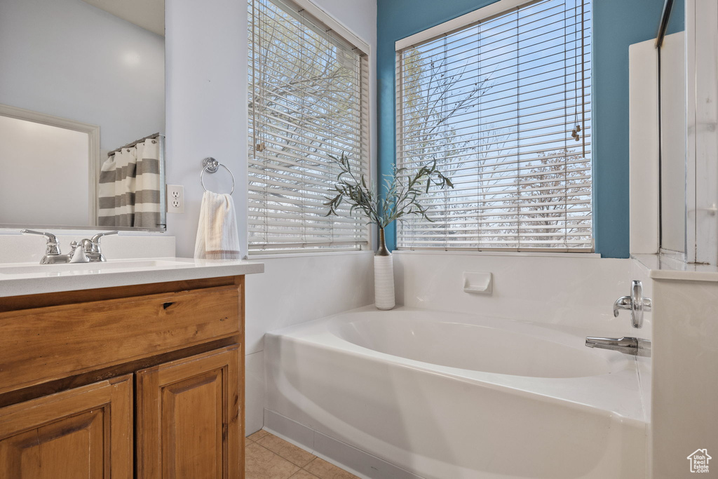 Bathroom featuring tile patterned floors, a garden tub, vanity, and a healthy amount of sunlight
