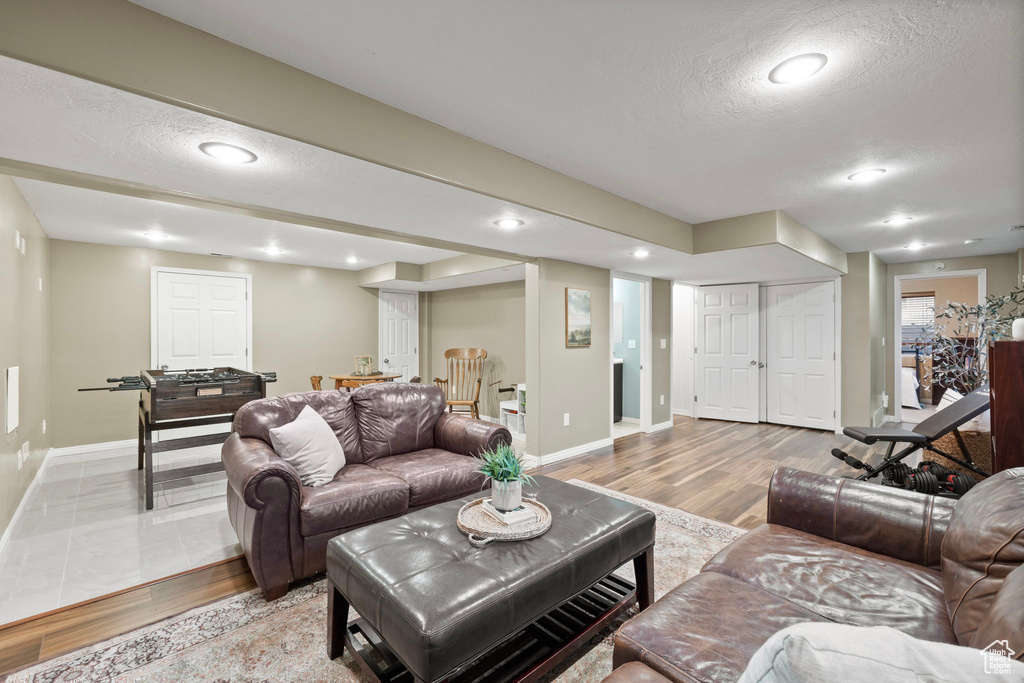 Living room with baseboards, a textured ceiling, and light wood finished floors