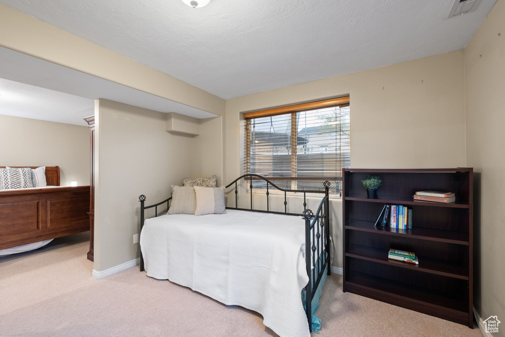 Carpeted bedroom featuring baseboards, visible vents, and a textured ceiling