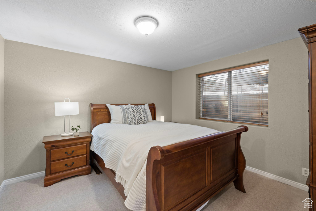Bedroom featuring baseboards, a textured ceiling, and light carpet