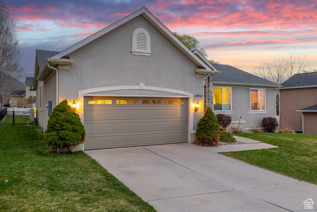 View of front of property with concrete driveway, stucco siding, fence, and a front lawn