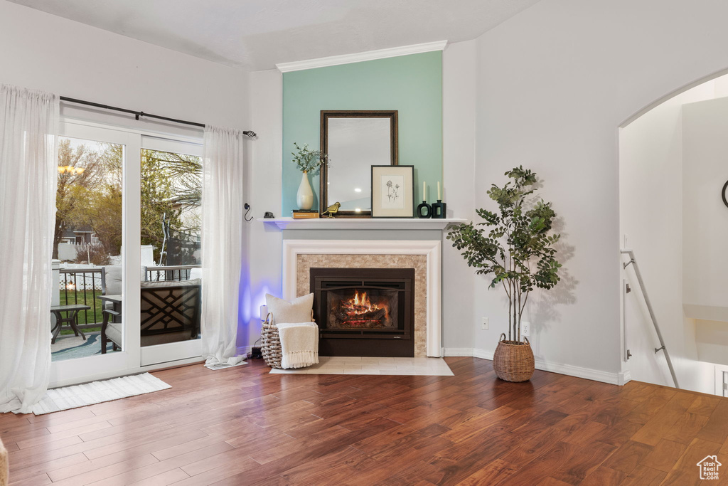 Unfurnished living room featuring a fireplace with flush hearth, arched walkways, wood finished floors, and vaulted ceiling