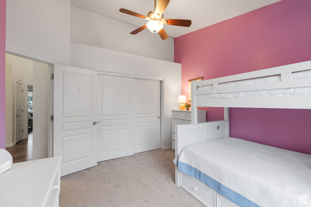 Bedroom with light colored carpet, high vaulted ceiling, a closet, and ceiling fan