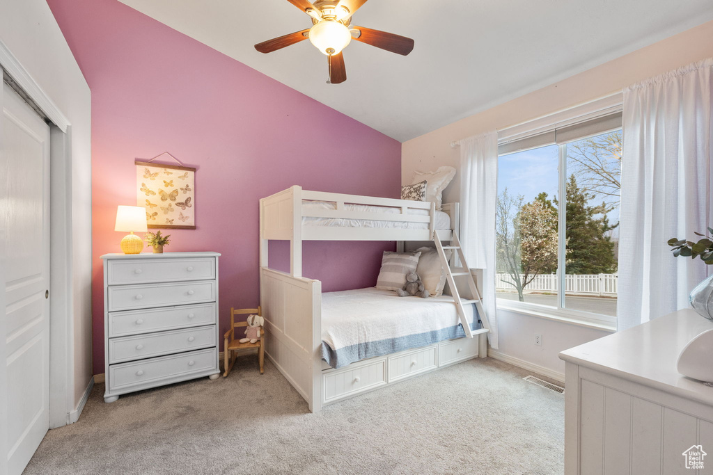 Carpeted bedroom featuring a closet, visible vents, baseboards, a ceiling fan, and lofted ceiling