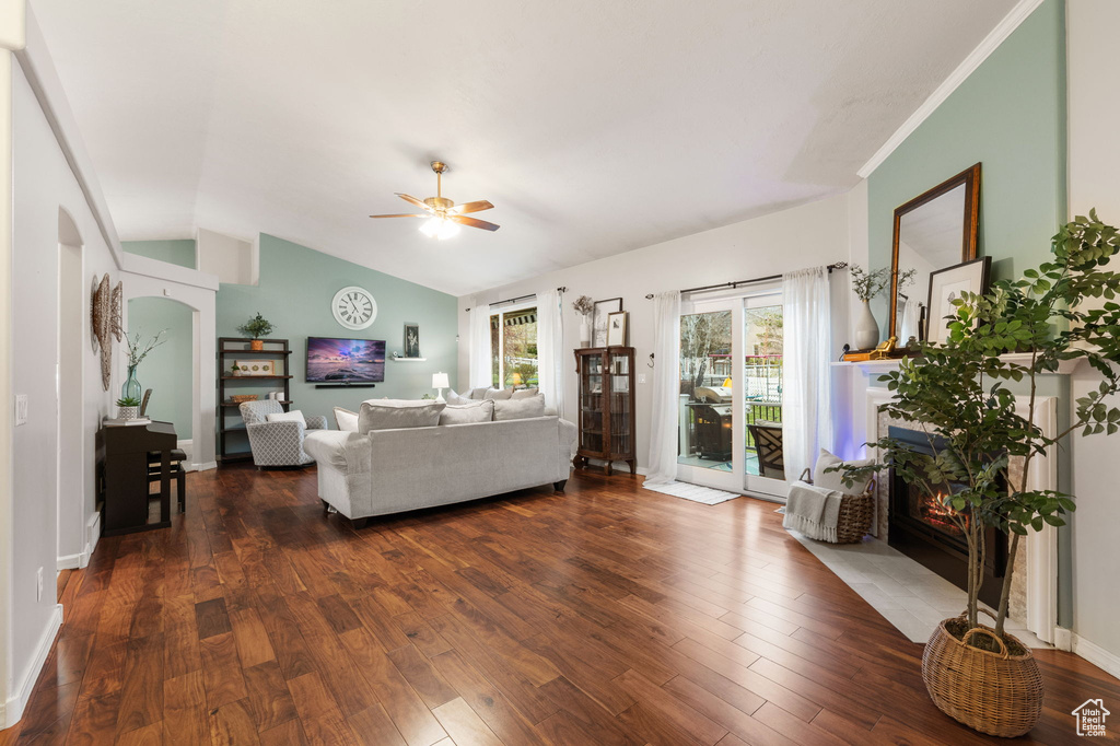 Living area featuring baseboards, dark wood-style floors, vaulted ceiling, and ceiling fan