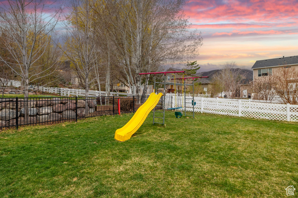 Playground at dusk with a yard, fence, and a playground