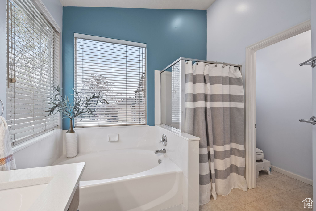 Bathroom featuring tile patterned flooring, vanity, toilet, curtained shower, and a bath