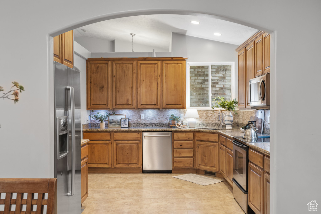 Kitchen featuring a sink, lofted ceiling, decorative backsplash, and appliances with stainless steel finishes
