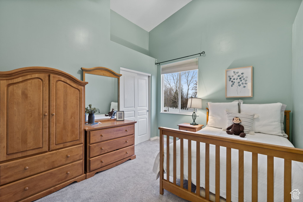 Bedroom featuring a closet, high vaulted ceiling, and carpet