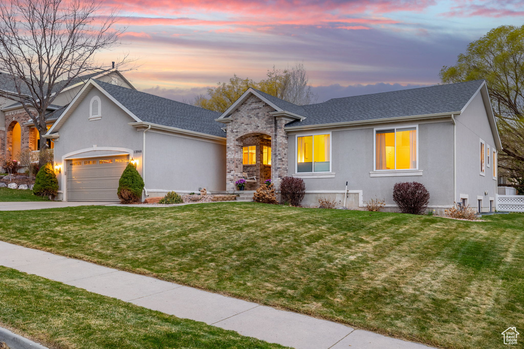 View of front of home with stucco siding, an attached garage, a front yard, and driveway