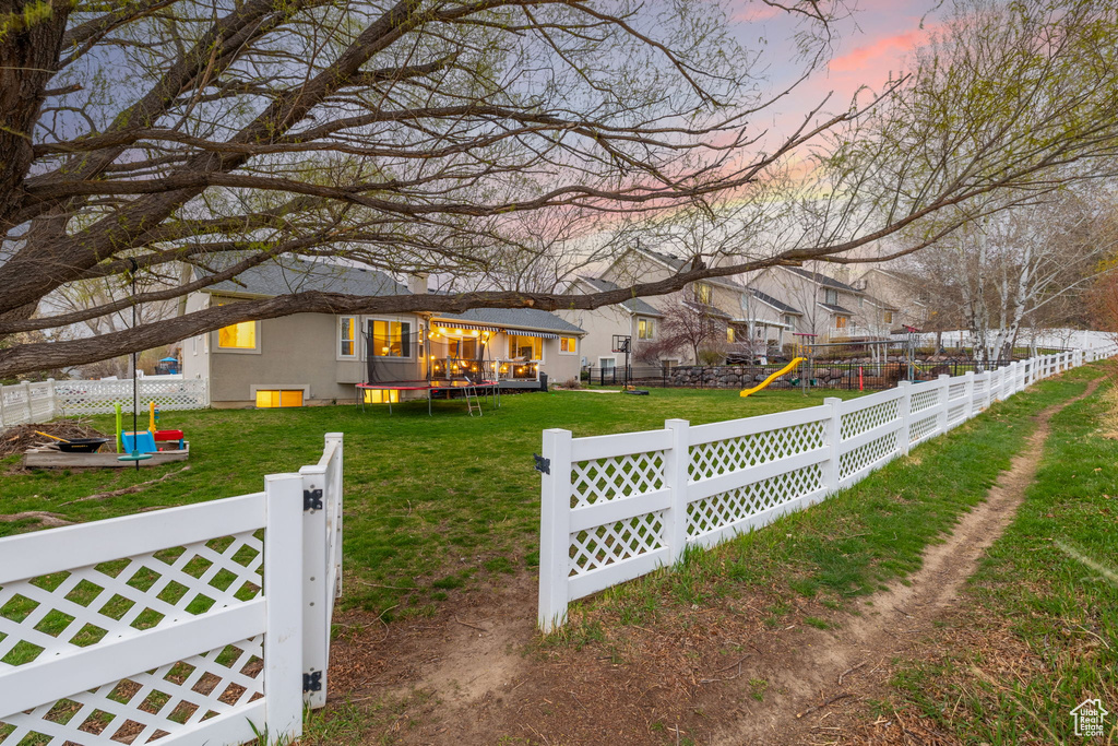 View of yard featuring a trampoline, a playground, and a fenced backyard