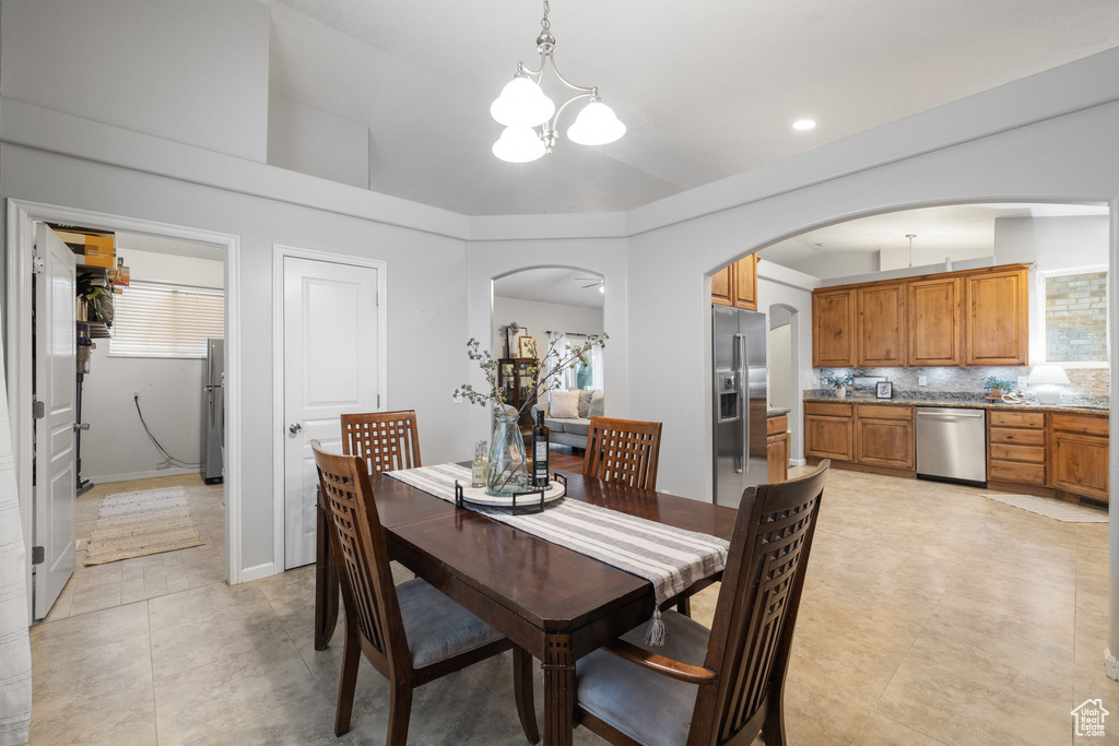 Dining room with a notable chandelier, arched walkways, and light tile patterned floors