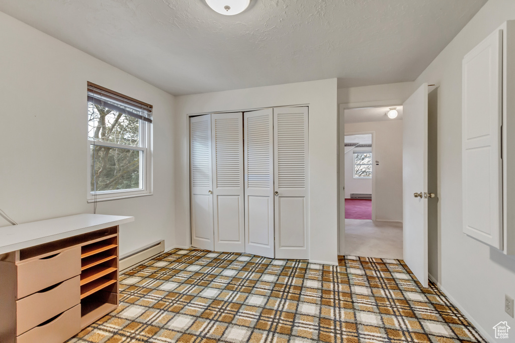 Unfurnished bedroom featuring baseboards, baseboard heating, a closet, and a textured ceiling