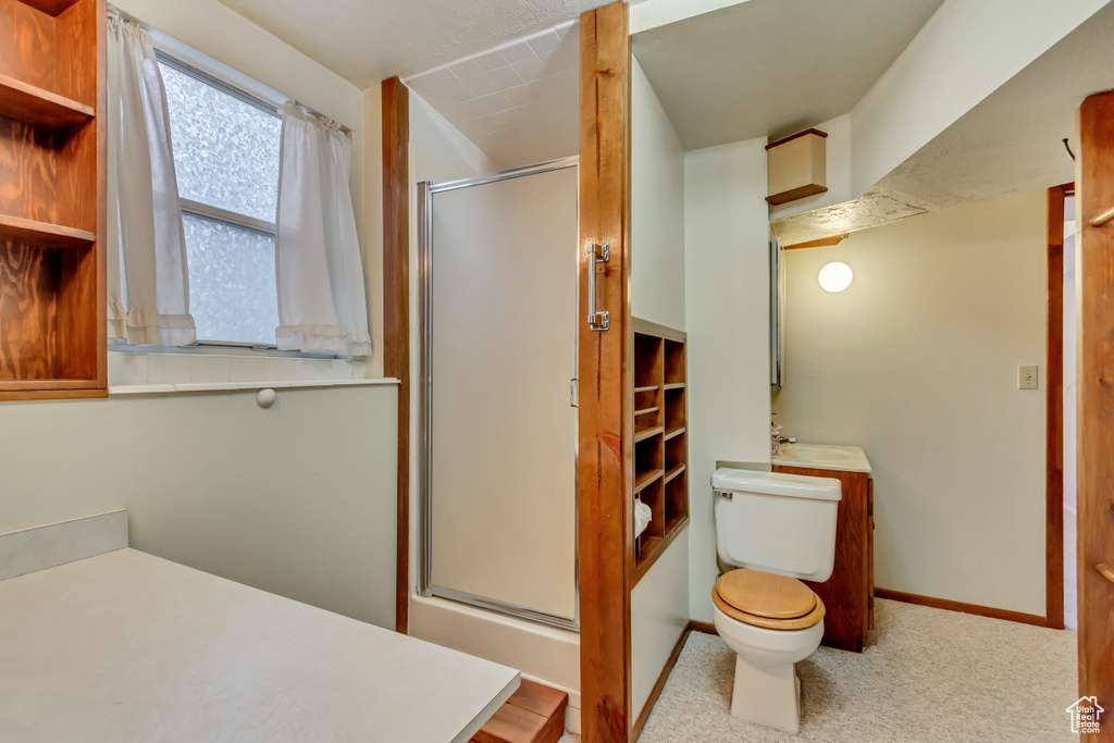 Full bathroom with a stall shower, baseboards, toilet, and a sink