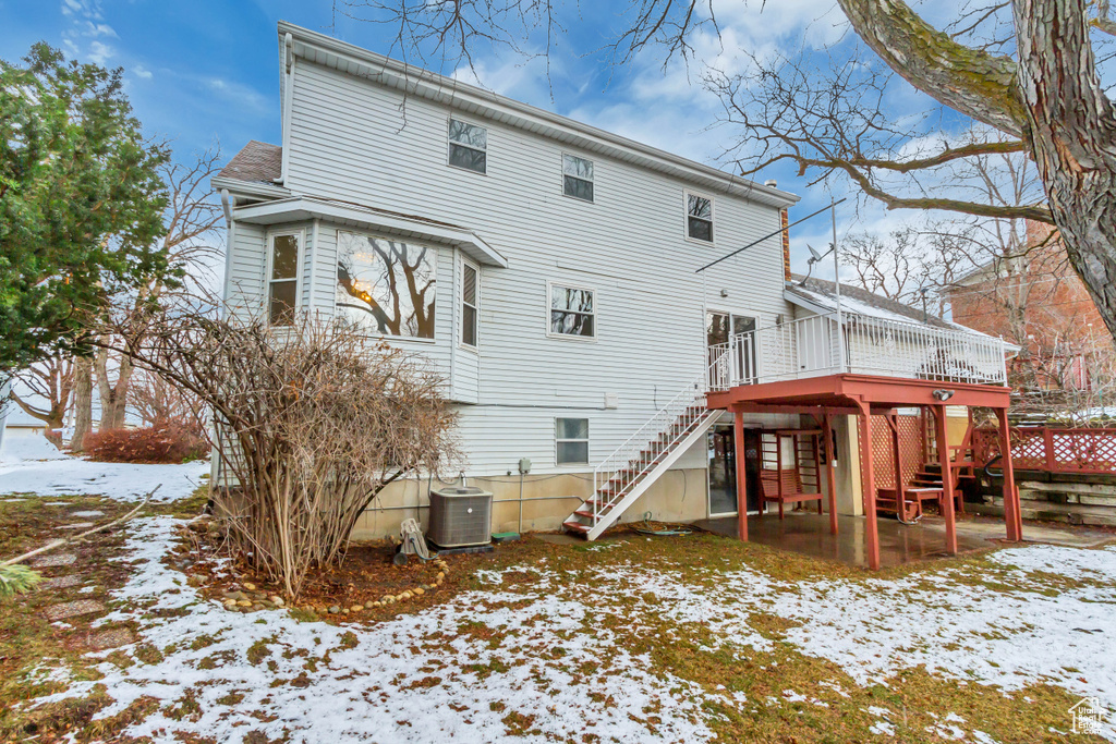 Snow covered back of property featuring cooling unit, a patio, stairs, and a wooden deck