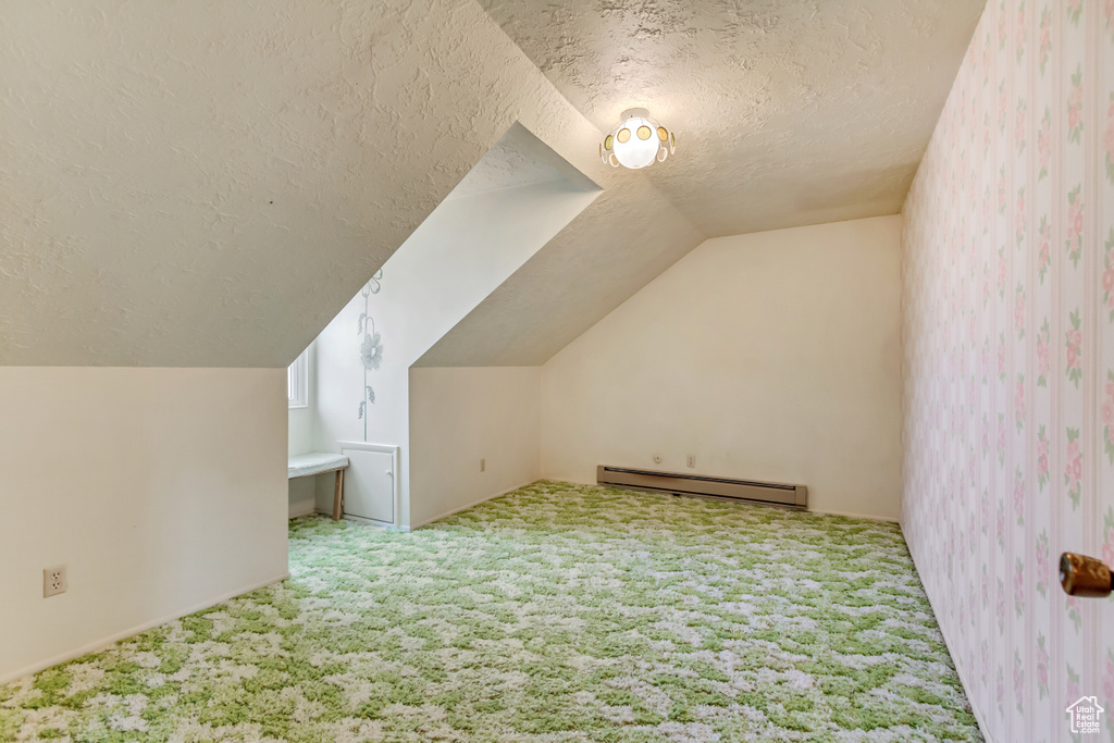 Bonus room featuring a baseboard radiator, lofted ceiling, carpet floors, and a textured ceiling