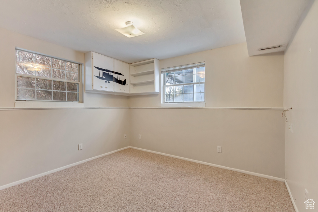 Empty room featuring baseboards, carpet floors, and a textured ceiling