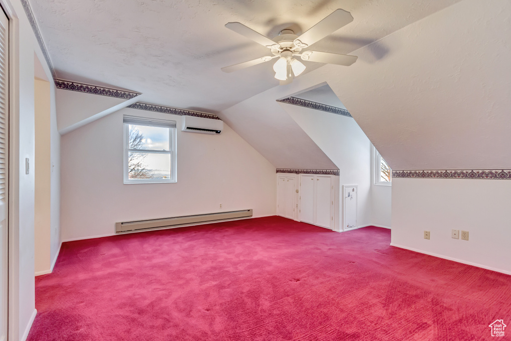 Additional living space featuring a baseboard radiator, vaulted ceiling, ceiling fan, and carpet