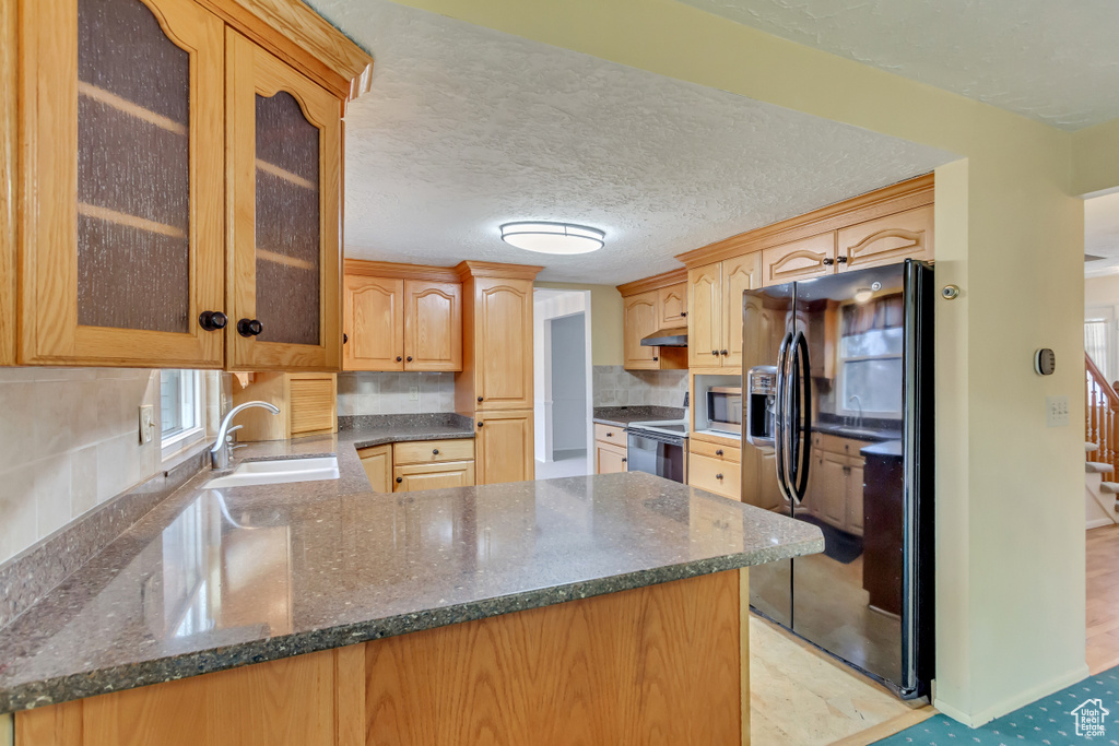 Kitchen with black fridge, stainless steel microwave, a sink, electric range oven, and a peninsula