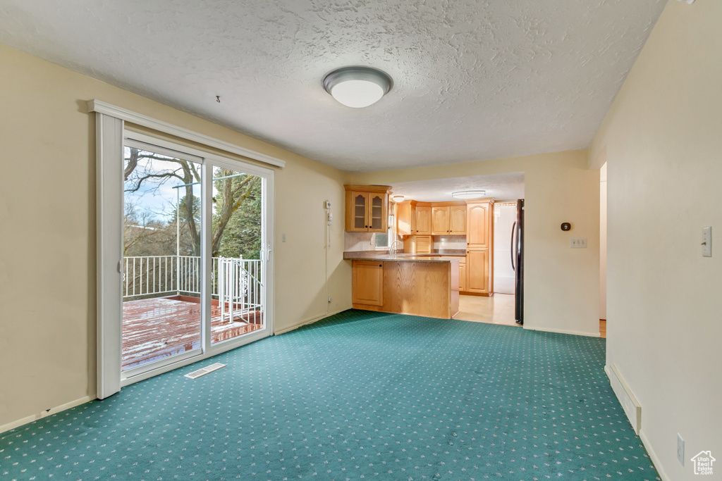 Unfurnished living room with baseboards, a textured ceiling, visible vents, and light carpet
