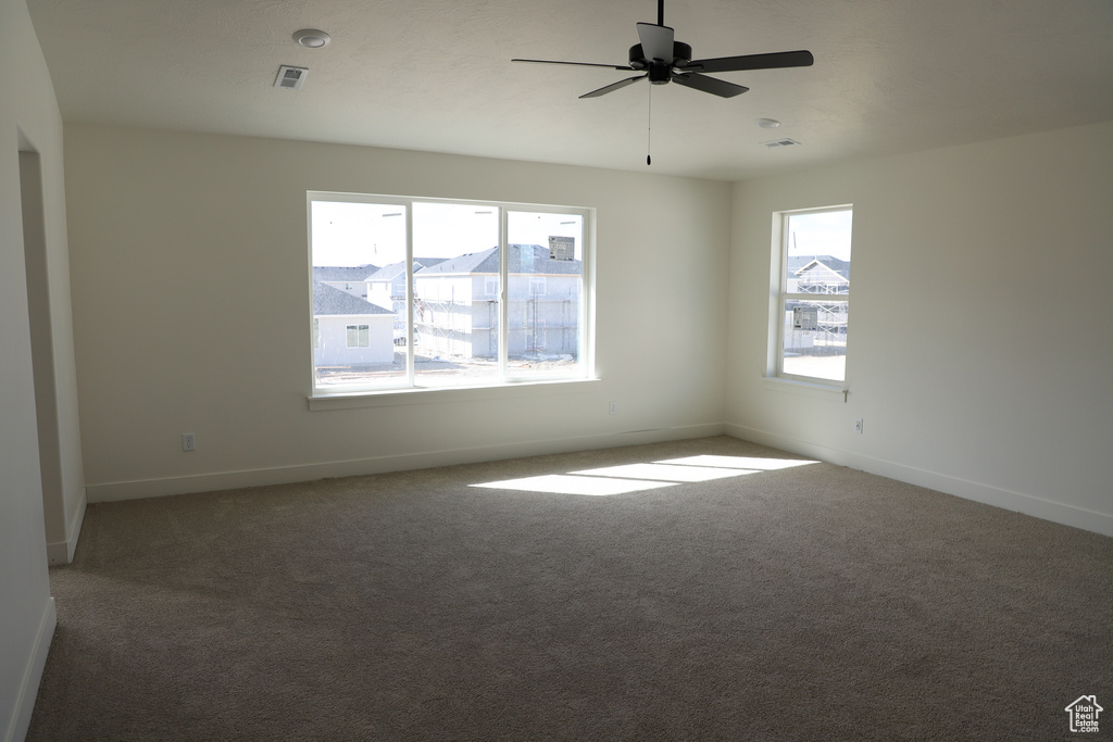 Spare room featuring carpet floors, baseboards, visible vents, and ceiling fan