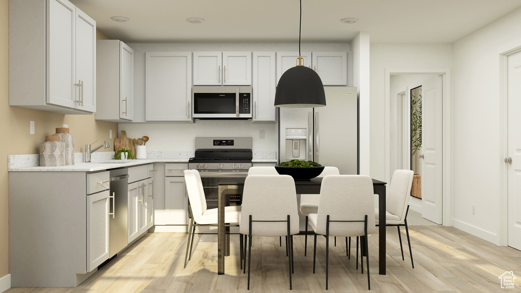 Kitchen featuring a sink, stainless steel appliances, baseboards, and light wood-type flooring