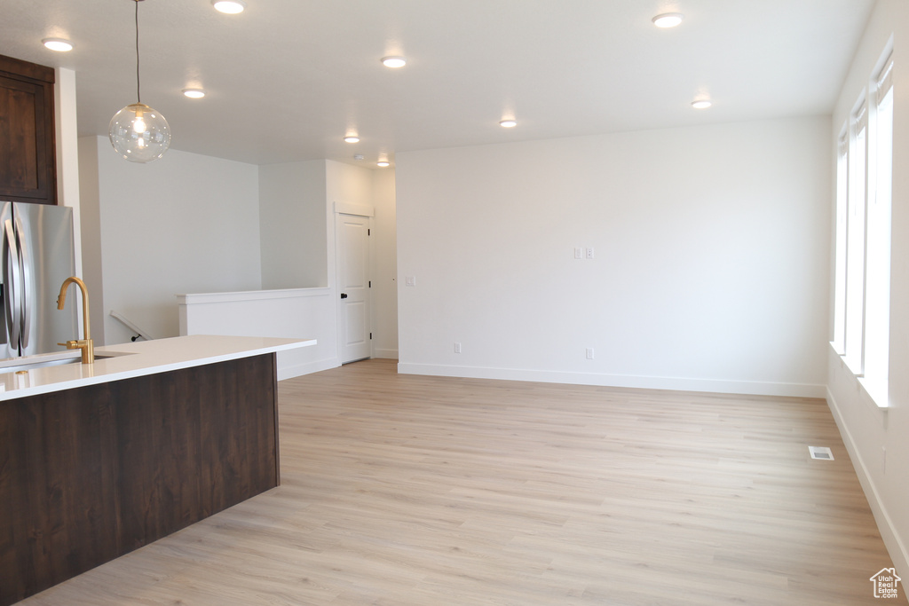 Kitchen featuring light wood-style flooring, dark brown cabinets, a healthy amount of sunlight, a sink, and stainless steel refrigerator with ice dispenser