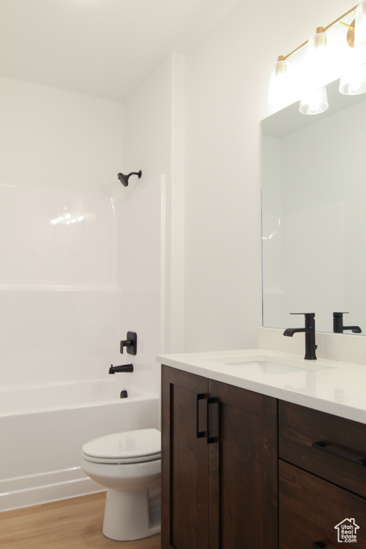 Full bath featuring toilet, wood finished floors, vanity, and  shower combination