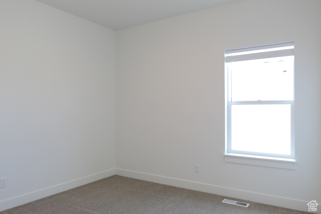 Carpeted spare room featuring baseboards and visible vents