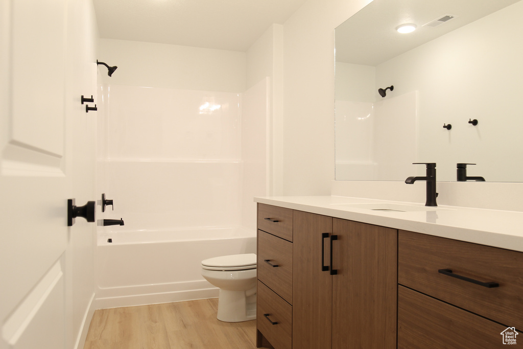 Full bath featuring shower / bath combination, toilet, visible vents, vanity, and wood finished floors