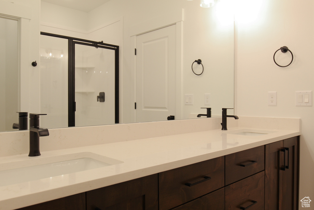 Full bath featuring a shower stall, double vanity, and a sink