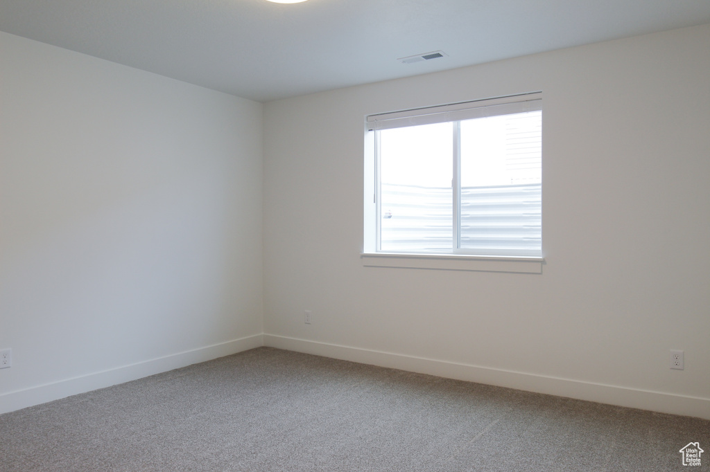 Unfurnished room featuring baseboards, visible vents, and light colored carpet