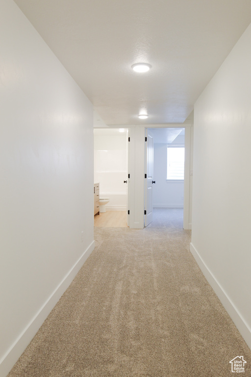 Hall featuring light carpet and baseboards