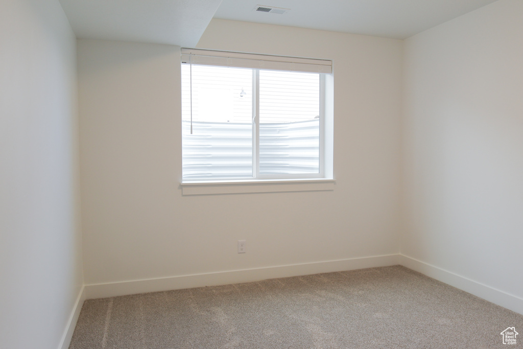 Empty room with baseboards, visible vents, and carpet floors