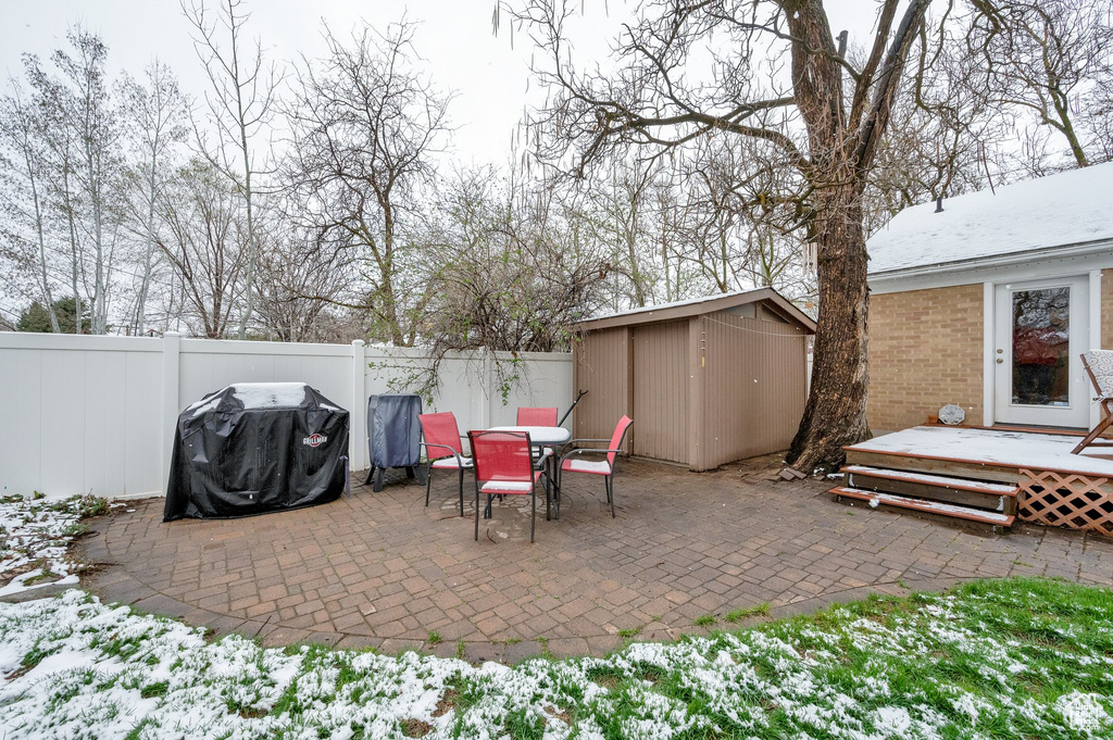 View of patio with a wooden deck, a fenced backyard, a grill, an outbuilding, and a shed
