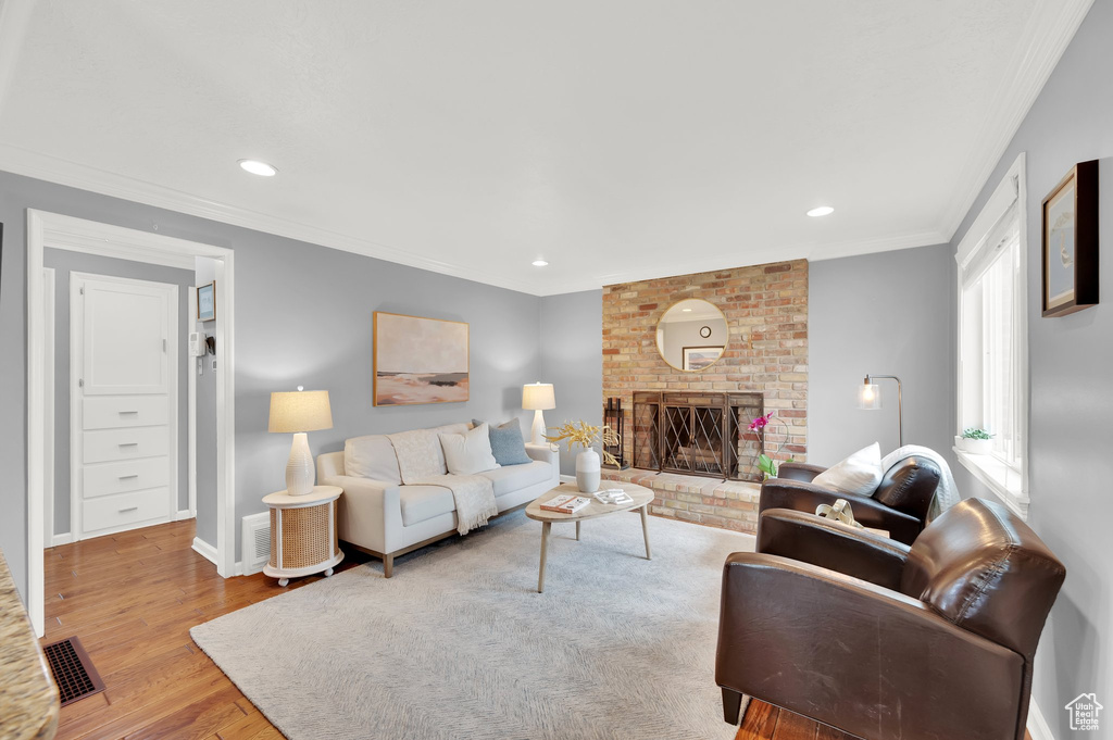 Living room featuring ornamental molding, baseboards, visible vents, a fireplace, and wood finished floors
