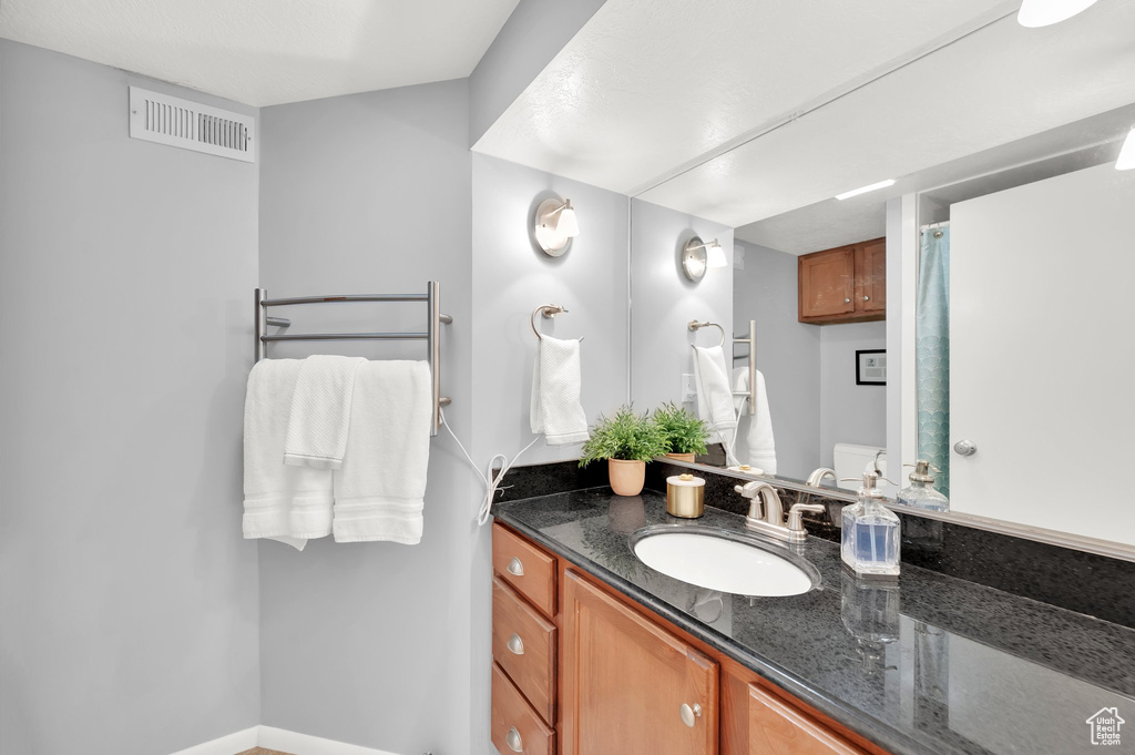 Full bathroom with baseboards, visible vents, toilet, and vanity