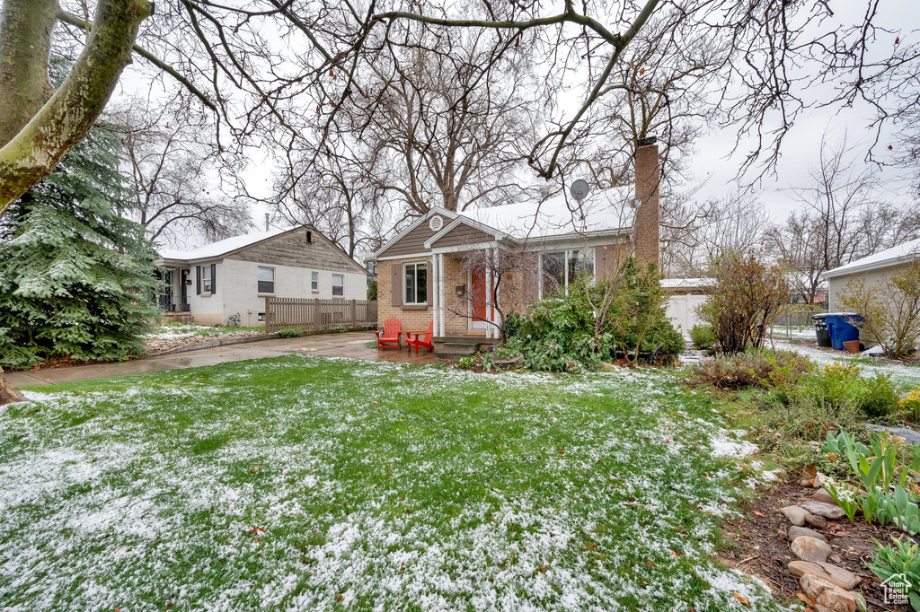 View of front of property with brick siding, a front yard, fence, and a chimney
