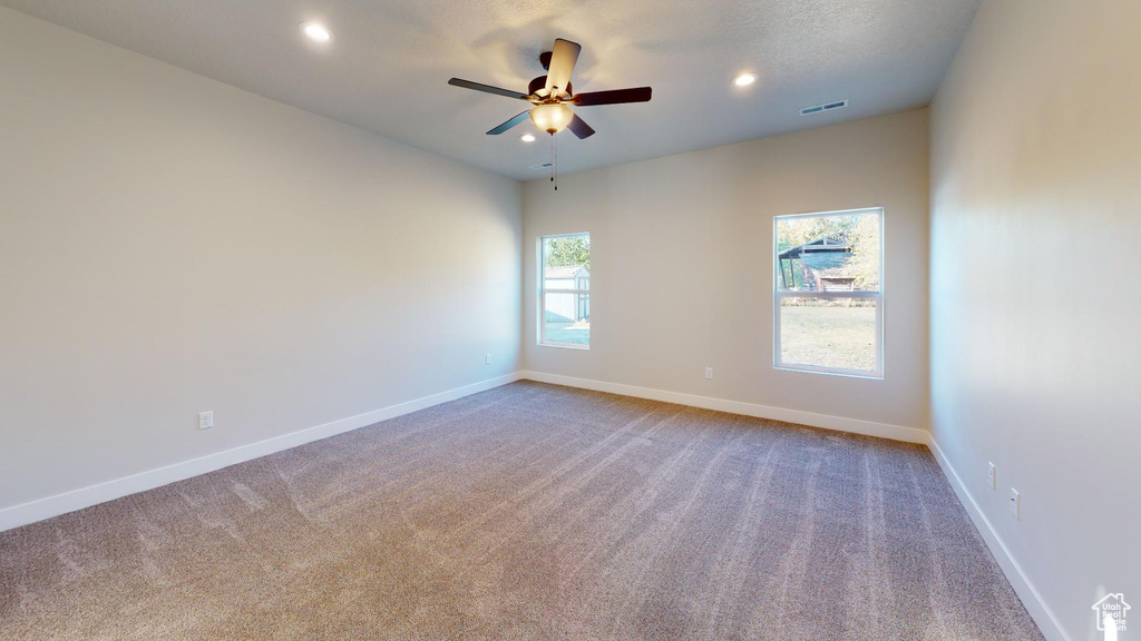 Carpeted empty room with baseboards, visible vents, ceiling fan, and recessed lighting