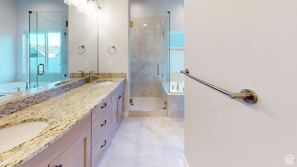 Bathroom with a stall shower, double vanity, a sink, and a garden tub