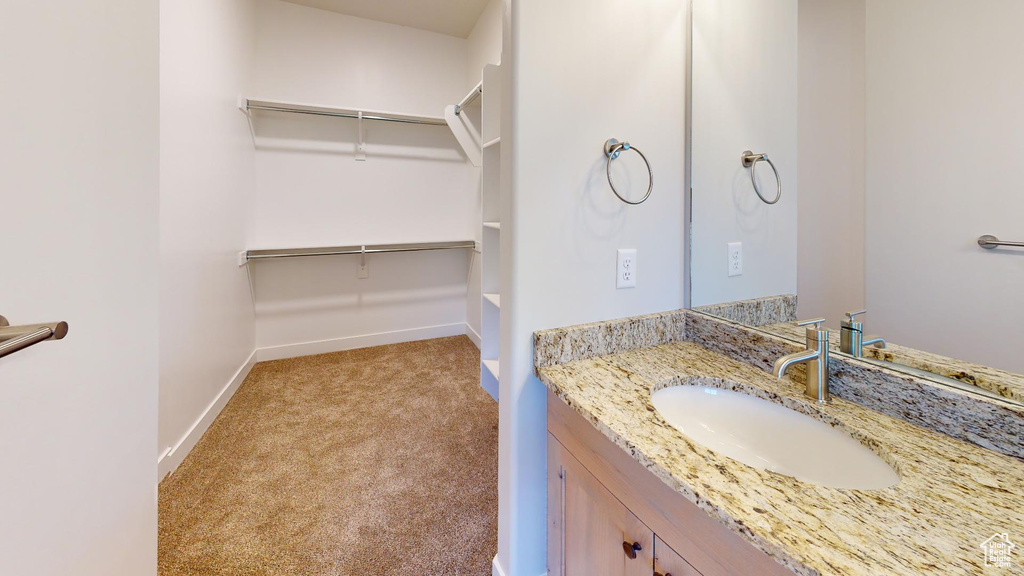 Bathroom with vanity, a walk in closet, and baseboards