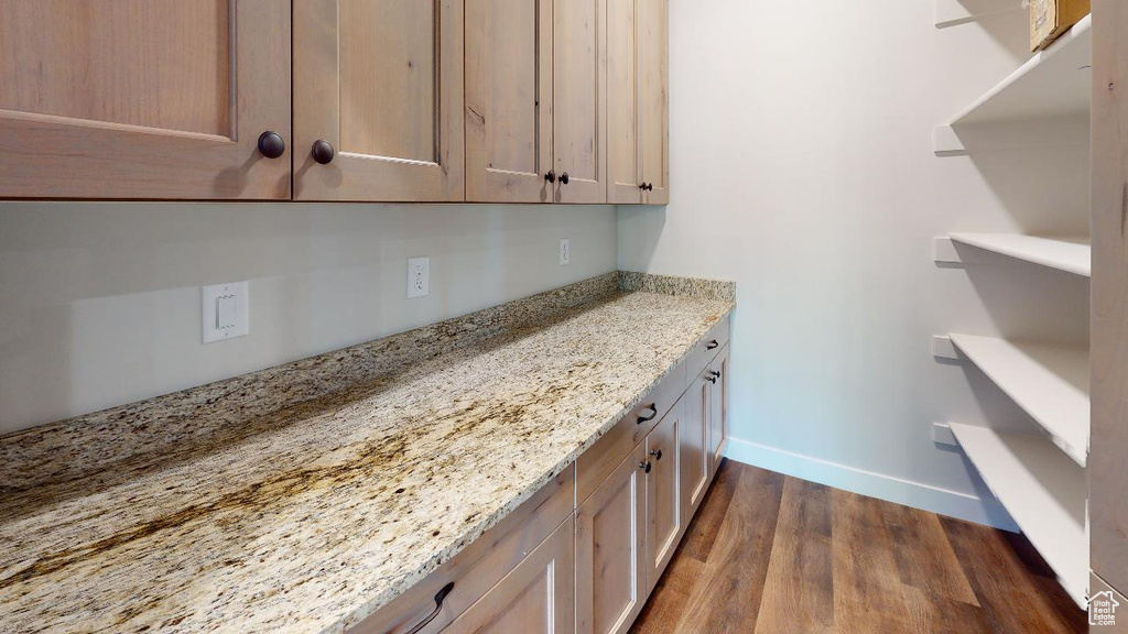 Interior space with baseboards, light stone counters, dark wood-type flooring, and open shelves