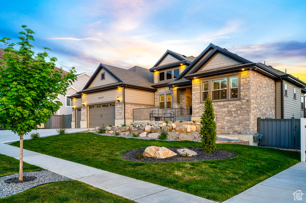 Craftsman-style house with stone siding, a front yard, and fence
