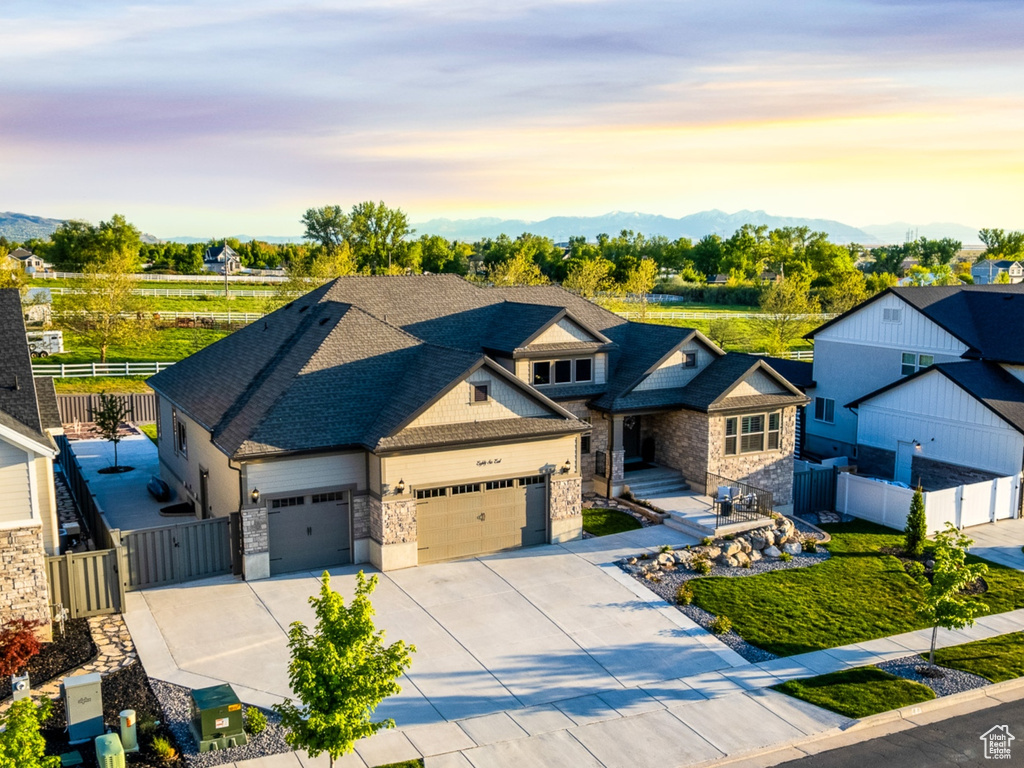 View of front of home featuring driveway, fence, a residential view, stone siding, and a gate