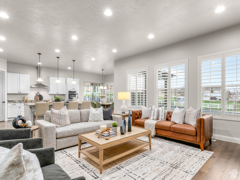 Living room featuring recessed lighting, a textured ceiling, baseboards, and light wood-type flooring