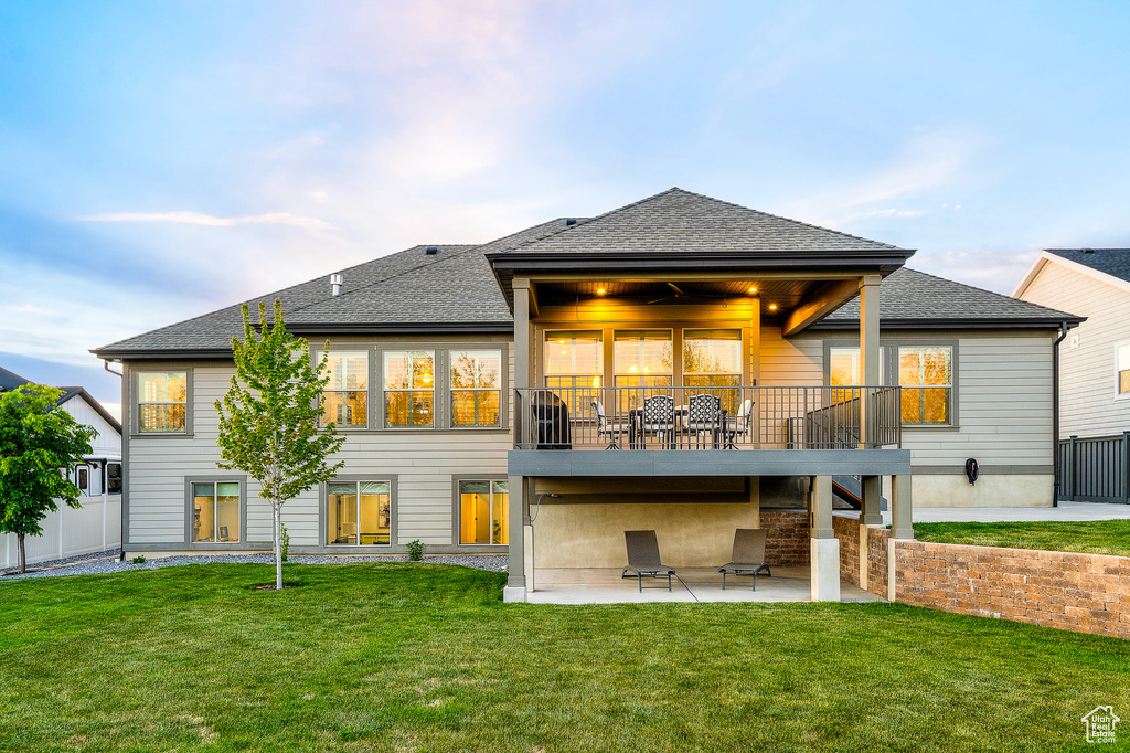 Back of house with a yard, a patio area, a shingled roof, and fence