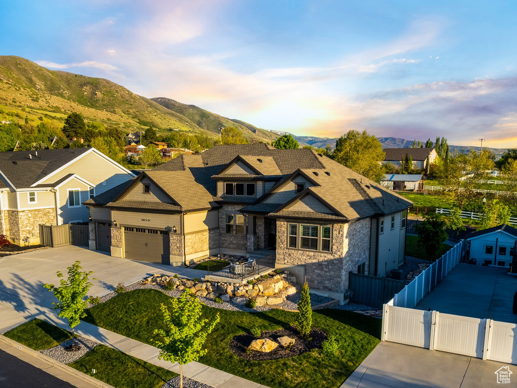 View of front of home with a mountain view, fence, a residential view, concrete driveway, and a gate